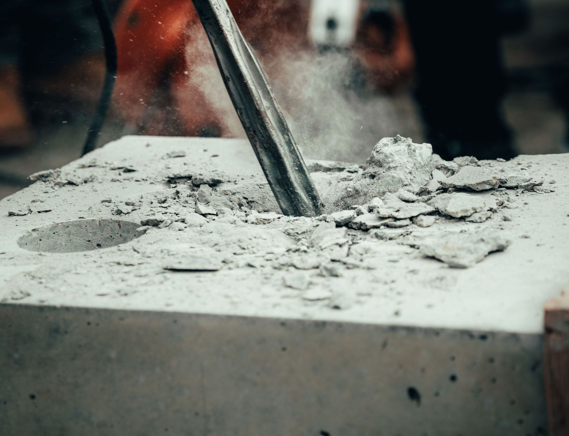 A detailed close-up of a power tool chipping away at a concrete block, capturing action and dust.